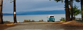 A VW bus at the end of a road leading to a lake