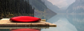 Red canoes on a pier on a still lake.