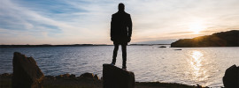 Person standing on a rock at sunset